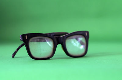 Close-up of sunglasses against green background