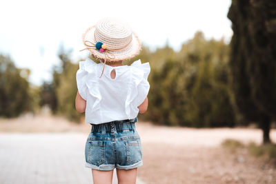 Little girl 3-4 year old standing in park outdoors. back view.