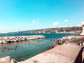 People on beach against blue sky