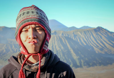 Portrait of young man standing against mountains during winter