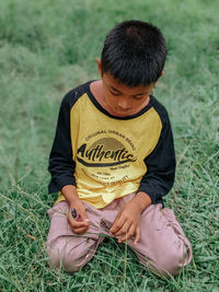 Side view of boy sitting on field