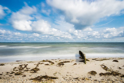 Scenic view of beach against cloudy sky