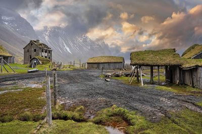 Tiretracks by traditional houses in viking village against cloudy sky at sunset