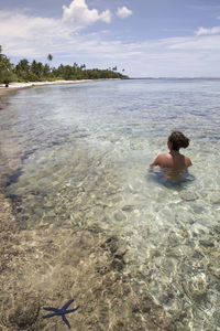 Rear view of man on beach against sky