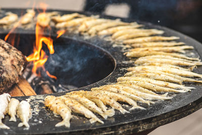 Preparing traditional tasty fried european smelt fish cooked on an open fire in a street food market