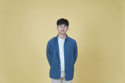 Portrait of teenage boy standing against wall