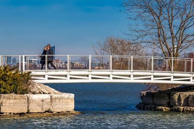 Man standing on bridge over river against clear sky