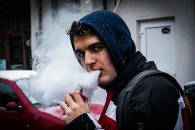 Portrait of young man smoking pipe cigarette during winter