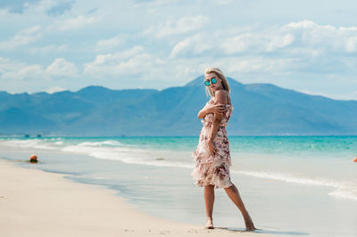 Full length of woman standing on beach against sky