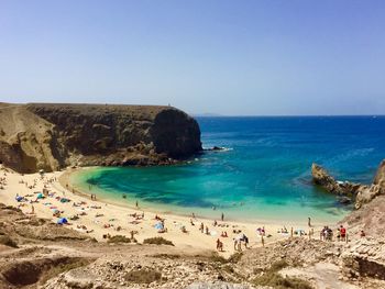 Scenic view of people on beach against clear sky