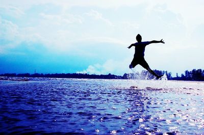 Full length of man jumping in sea against sky