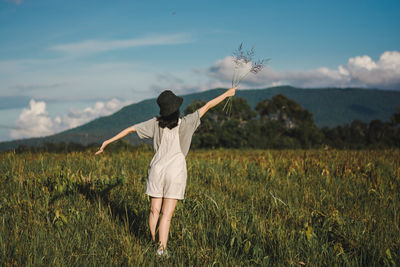 Rear view of woman standing on field against sky