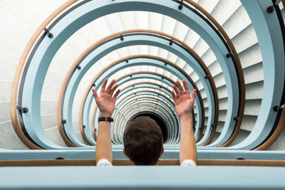 High angle view of man gesturing at spiral staircase