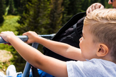 Small boy enjoying the ride on chairlift while having vacation with his dad.