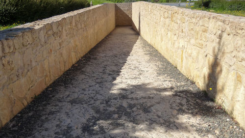 Shadow of stone wall on footpath