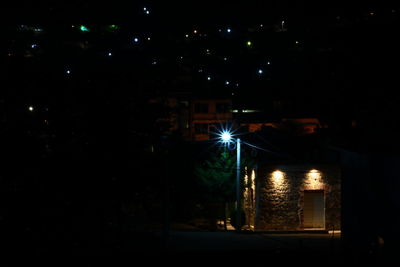 Illuminated street amidst buildings in city at night