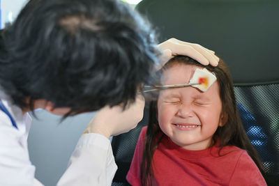 Doctor treating girl with injured head at clinic