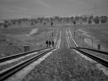 People walking on railroad track against sky