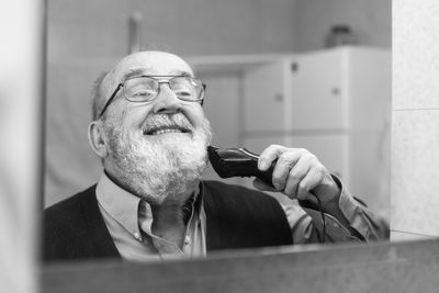 Reflection of senior man shaving in bathroom