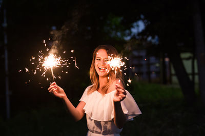 Smiling woman with sparklers at night