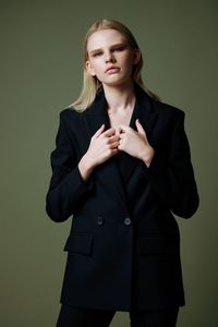 Portrait of young woman standing against black background