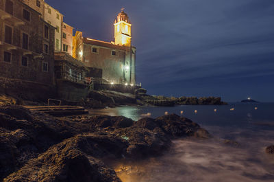 Lighthouse by sea against sky at night