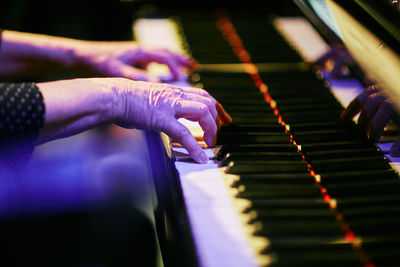 Cropped wrinkled hands of musician playing piano