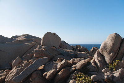 Rocks by sea against clear blue sky