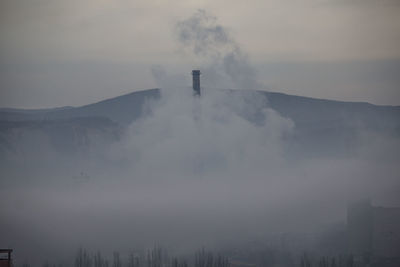 Smoke emitting from factory against sky