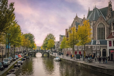 Bridge over river amidst buildings in city against sky