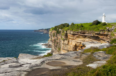 Macquarie lighthouse on rock formation at watsons bay against sky