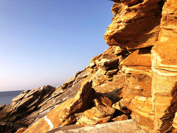 Rock formations in sea against clear sky