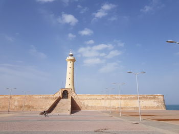 Low angle view of lighthouse by building against sky