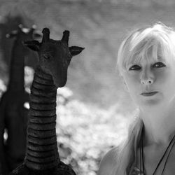 Portrait of woman with blond hair standing by sculpture