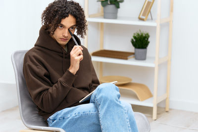 Young woman using mobile phone while sitting at home