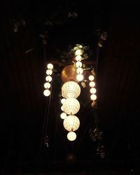 Low angle view of illuminated light bulb hanging at night