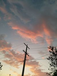 Low angle view of silhouette electricity pylon against dramatic sky