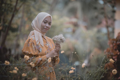 Woman standing by flowering plants on field