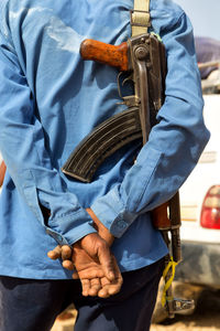 Midsection of man holding rifle