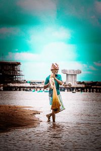 Woman walking at beach against sky