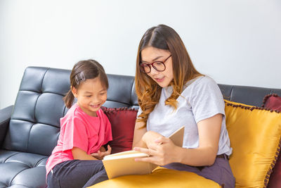 Rear view of mother and daughter sitting on floor