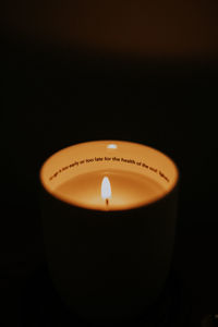 Close-up of lit candle against black background