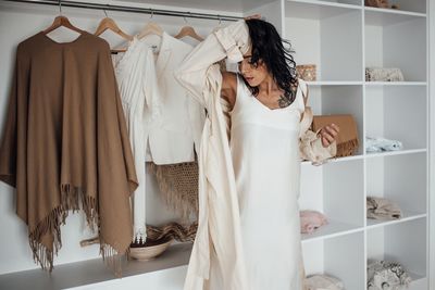 Woman in white dress against wardrobe at home