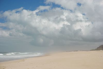 Scenic view of beach against cloudy sky