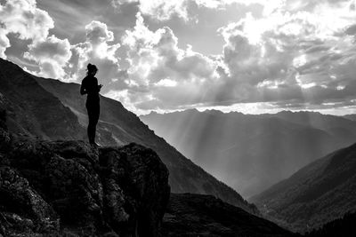 Silhouette woman standing on rock against sky