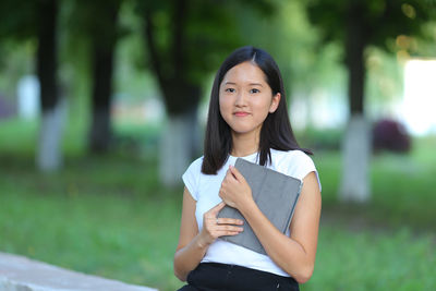 Young woman using laptop while sitting on field