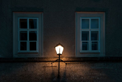 Illuminated street light against building