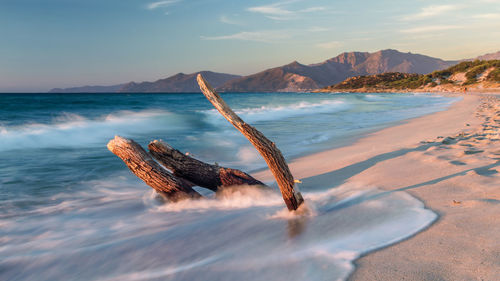 View of waves in sea against mountain range