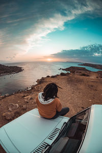 Rear view of woman sitting on beach