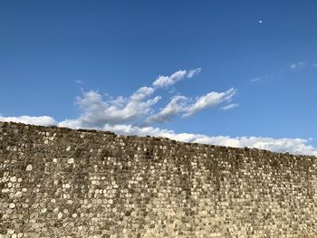 Low angle view of wall against blue sky